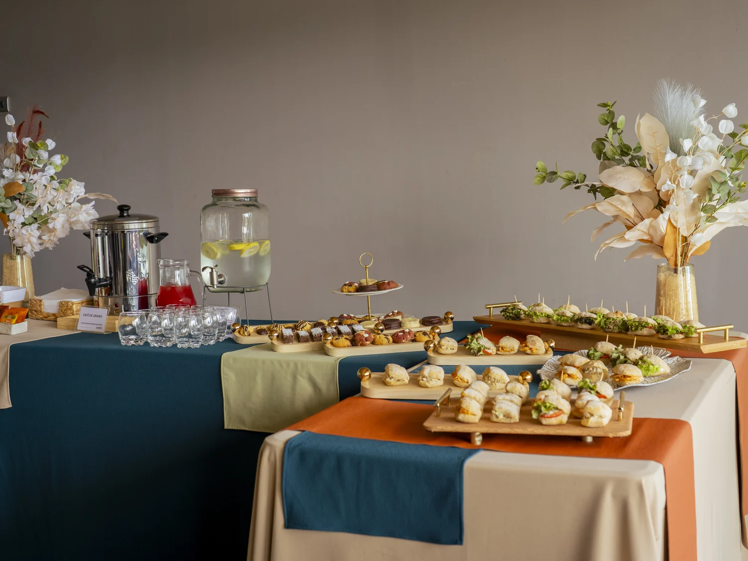 La mesa completa de un coffee break de Gustito, con dulces, sándwiches y agua saborizada